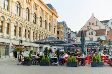 RIGA, LATVIA - 9 AĞUSTOS 2023: Kasaba halkı ve şehir misafirleri Riga 'daki renkli kaldırım taşlı caddelerde geziniyorlar. Letonya 'nın başkentinde canlı bir şehir hayatı.