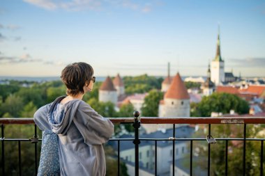 Genç kız güneşli bir yaz sabahında Tallinn Old Town 'ın ikonik gökyüzü manzarasına hayran. UNESCO Dünya Mirası sahası, Estonya.