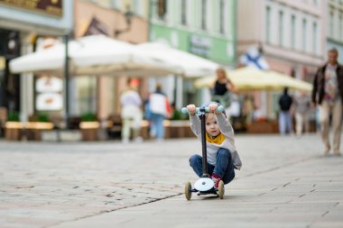Tallinn Eski Kenti veya Tallinna Valalinn 'in renkli ortaçağ caddelerinde motosikletine binen sevimli küçük çocuk UNESCO Dünya Mirasları Listesi' ne dahil. Estonya başkentini keşfeden çocuk.