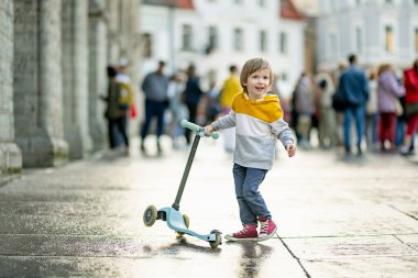 Tallinn Eski Kenti veya Tallinna Valalinn 'in renkli ortaçağ caddelerinde motosikletine binen sevimli küçük çocuk UNESCO Dünya Mirasları Listesi' ne dahil. Estonya başkentini keşfeden çocuk.