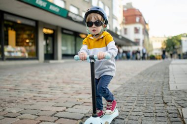 Tallinn Eski Kenti veya Tallinna Valalinn 'in renkli ortaçağ caddelerinde motosikletine binen sevimli küçük çocuk UNESCO Dünya Mirasları Listesi' ne dahil. Estonya başkentini keşfeden çocuk.