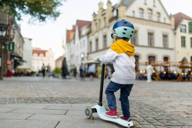 Tallinn Eski Kenti veya Tallinna Valalinn 'in renkli ortaçağ caddelerinde motosikletine binen sevimli küçük çocuk UNESCO Dünya Mirasları Listesi' ne dahil. Estonya başkentini keşfeden çocuk.