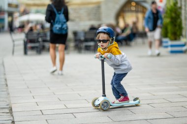 Tallinn Eski Kenti veya Tallinna Valalinn 'in renkli ortaçağ caddelerinde motosikletine binen sevimli küçük çocuk UNESCO Dünya Mirasları Listesi' ne dahil. Estonya başkentini keşfeden çocuk.