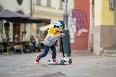 Tallinn Eski Kenti veya Tallinna Valalinn 'in renkli ortaçağ caddelerinde motosikletine binen sevimli küçük çocuk UNESCO Dünya Mirasları Listesi' ne dahil. Estonya başkentini keşfeden çocuk.