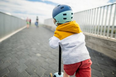 Tallinn limanında küçük şirin bir çocuk scooter kullanıyor. Küçük çocuklar için aktif eğlence.