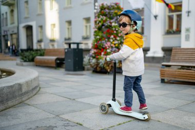 Tallinn Eski Kenti veya Tallinna Valalinn 'in renkli ortaçağ caddelerinde motosikletine binen sevimli küçük çocuk UNESCO Dünya Mirasları Listesi' ne dahil. Estonya başkentini keşfeden çocuk.