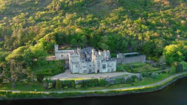 Gün batımında Kylemore Manastırı 'nda. Kylemore Kalesi 'nde kurulan bir Benedikt manastırı. Connemara güneşli yaz akşamı hava manzarası. Galway İlçesi, İrlanda. Hız rampası etkisi.