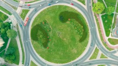 Aerial timelapse top-down view of a roundabout or traffic circle, looping road junction on summer day. City traffic concept. Birds eye view modern urban city landscape. City of Vilnius, Lithuania,