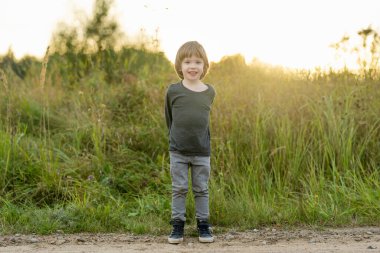 Güneşli bir sonbahar gününde dışarıda oynayan sevimli bir çocuk. Doğayı keşfeden çocuk. Küçük çocuklar için sonbahar aktiviteleri.