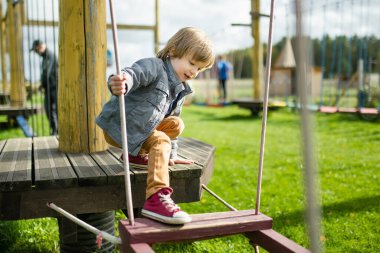 Tatlı çocuk, sıcak bir sonbahar gününde dışarıda oyun alanında eğleniyor. Sonbaharda çocuklar için aktif eğlence.