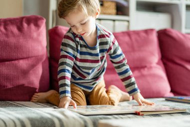 Parlak, güneşli bir öğleden sonra evdeki kanepede kitap okuyan sevimli küçük bir çocuk. Gündüz kreşinde yaratıcı aktivite. Çocuklar eğleniyor. Eğitici öğrenme oyunları.