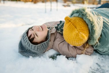 Sevimli genç kızlar kışın eğleniyorlar. Karda oynayan sevimli çocuklar. Çocuklu aileler için eğlenceli kış aktiviteleri.