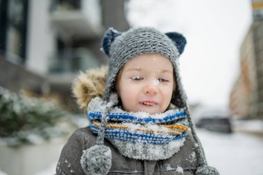 Karlı bir kış gününde küçük sevimli bir çocuk şehirde eğleniyor. Karda oynayan, kalın giysiler giymiş şirin bir çocuk. Çocuklu aileler için kış etkinlikleri.