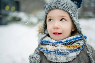 Karlı bir kış gününde küçük sevimli bir çocuk şehirde eğleniyor. Karda oynayan, kalın giysiler giymiş şirin bir çocuk. Çocuklu aileler için kış etkinlikleri.