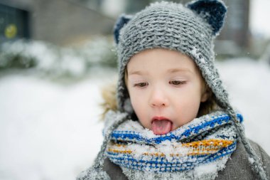 Karlı bir kış gününde küçük sevimli bir çocuk şehirde eğleniyor. Karda oynayan, kalın giysiler giymiş şirin bir çocuk. Çocuklu aileler için kış etkinlikleri.