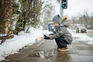 Karlı bir kış gününde küçük sevimli bir çocuk şehirde eğleniyor. Karda oynayan, kalın giysiler giymiş şirin bir çocuk. Çocuklu aileler için kış etkinlikleri.