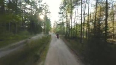 Güneşli yaz ormanlarında hafif dayanıklı bisiklet süren profesyonel motosikletli bir motorcunun havadan çekilmiş görüntüleri. Motokros sporu, off-road motosiklet yarışı macerası.