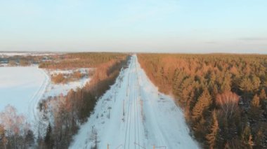 Kışın çam ormanları arasında bir demiryolunun hava günbatımı manzarası. Litvanya, Vilnius 'ta kış manzarası.