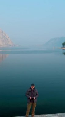 Drone pilotu uçağını Como Gölü kıyısına indiriyor. Lecco şehrinin dikey gün batımı manzarası. Lecco kasabasının resimli rıhtımı Como Gölü ve Bergamo Alpleri arasında yer alıyor. İtalya.