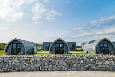 INISHMORE, IRELAND - MAY 22, 2023: Glamping and camping houses near wide sandy Frenchman's beach on Inishmore, one of the largest of the Aran Islands in Galway Bay, Ireland. clipart