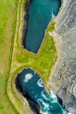 Aerial view of Bridges of Ross, three natural rock arches, carved into the cliffs by natural ocean erosion, on the west coast of Ross Bay, Wild Atlantic Way Discovery Point, County Clare, Ireland clipart