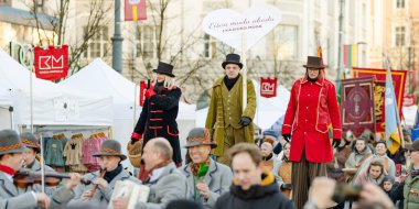 VILNIUS, LITHUANIA - MARCH 4, 2024: Cheerful people participating in humorous parade during Kaziuko muge or Kaziukas, traditional Easter market, crafts fair held every March on Old Town streets. clipart