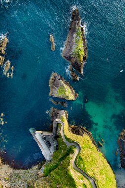 Dunquin or Dun Chaoin pier, Ireland's Sheep Highway. Aerial view of narrow pathway winding down to the pier, ocean coastline, cliffs. Popular iconic location on Slea Head Drive and Wild Atlantic Way. clipart