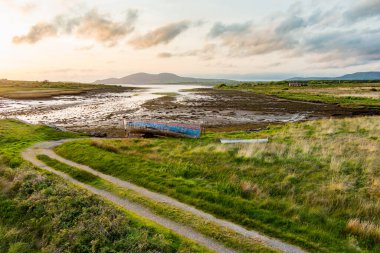 Eski tekne Kerry güzergahı Ring boyunca küçük bir plajda sol. Gün batımında Iveragh Yarımadası'nda Engebeli sahil, County Kerry, İrlanda.