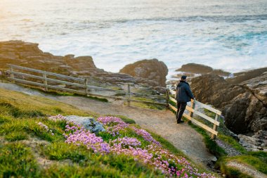 Tourist admiring scenic beauty of Malin Head, Ireland's northernmost point, Wild Atlantic Way, spectacular coastal route. Wonders of nature. Numerous Discovery Points. Co. Donegal clipart