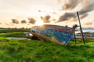 Eski tekne Kerry güzergahı Ring boyunca küçük bir plajda sol. Gün batımında Iveragh Yarımadası'nda Engebeli sahil, County Kerry, İrlanda.