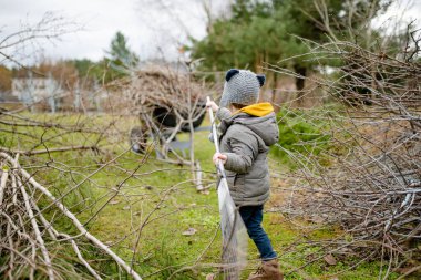 Küçük şirin çocuk bahar günü bahçe tırmığıyla oynuyor. Dört yaşındaki çocuk ev işlerine yardım ediyor. Çocuklar için aktif boş zaman.