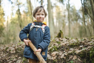 Güzel, güneşli bir bahar gününde ormanda yürüyüş yaparken eğlenen sevimli küçük çocuk. Çocuklarla aktif aile eğlencesi. Doğayı keşfeden çocuk.