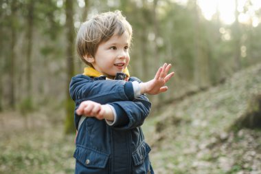 Güzel, güneşli bir bahar gününde ormanda yürüyüş yaparken eğlenen sevimli küçük çocuk. Çocuklarla aktif aile eğlencesi. Doğayı keşfeden çocuk.
