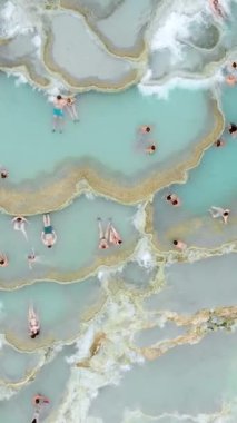 Terme di Saturnia 'nın havadan görünüşü, jeotermal sülfür yayları ve Saturnia termal banyolarında şelaleli doğal spa. Cascate del Mulino, Grosseto, Toskana, İtalya 'da banyo yapan insanlar. Dikey görüntüler.