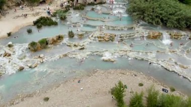 Terme di Saturnia 'nın hava manzarası, jeotermal sülfür yayları ve Saturnia termal banyolarında şelaleli doğal spa. Cascate del Mulino, Grosseto, Toskana, İtalya 'da yıkanan insanlar.