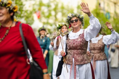 VILNIUS, LITHUANIA - 7 Temmuz 2024: Ulusal Litvanya Şarkı ve Dans Festivali geçit töreni sırasında geleneksel giysiler içinde neşeli insanlar grubu.