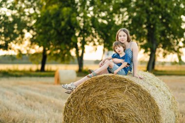 Ergen kız kardeş ve küçük erkek kardeşi bir yaz günü buğday tarlasında eğleniyorlar. Hasat zamanı saman balyasındaki çocuklar. Çocuklar dışarıda günbatımının keyfini çıkarıyorlar. Litvanya 'da mahsul hasat etmek.