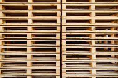 Düzenli bir ahşap palet yığını, ritmik çizgiler ve boşluklar yaratıyor, hepsi ağır nakliye, depolama ya da endüstriyel kullanıma hazır olduğunu gösteriyor..