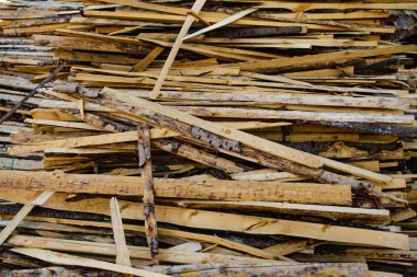 Kaba, düzensiz ahşap şeritler ve ağaç kabuğu kaplı tahtalar, muhtemelen ahşap kesikler ya da marangozluktan gelen hurda malzemeler..