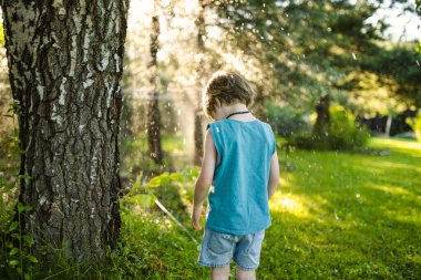 Komik küçük çocuk güneşli bir yaz gününde dışarıda eğleniyor. Çocuk bahçe fıskiyesinin altında koşuyor. Küçük çocuklar için yaz etkinlikleri.