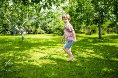 Sevimli küçük çocuk güneşli bir yaz gününde dışarıda eğleniyor. Çocuk dışarıda koşuyor. Doğayı keşfeden çocuk. Küçük çocuklar için yaz etkinlikleri.