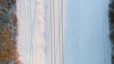 Kışın çam ormanları arasında bir demiryolunun yukarıdan aşağı gün batımı görüntüsü. Kış manzarası.