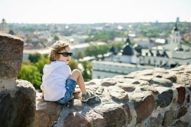 Bir çocuk Gediminas Tepesi 'nden Vilnius' un panoramik manzarasının keyfini çıkarıyor. Tarihin ve şehrin parlak yaz güneşinin altında buluştuğu yerden.