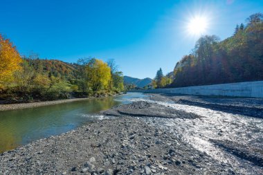 Güneşli bir günde bir dağ nehri ile sonbahar manzarası