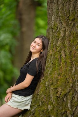 Büyük bir ağacın yanında bir kızın portresi.