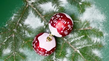 Yeşil arka planda Noel oyuncağı ve karlı ladin dalları