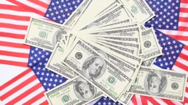 100 dolarlık banknotların ve Amerikan bayrağının döndüğü bir arka plan.