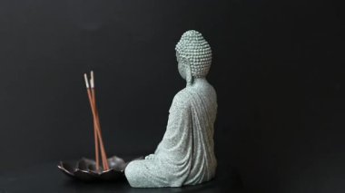 Stüdyoda siyah arka planda tütsü bulunan Buda heykelinin videosu.