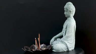 Stüdyoda siyah arka planda tütsü bulunan Buda heykelinin videosu.