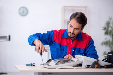 Genç tamirci atölyede ısıtıcıyı tamir ediyor.